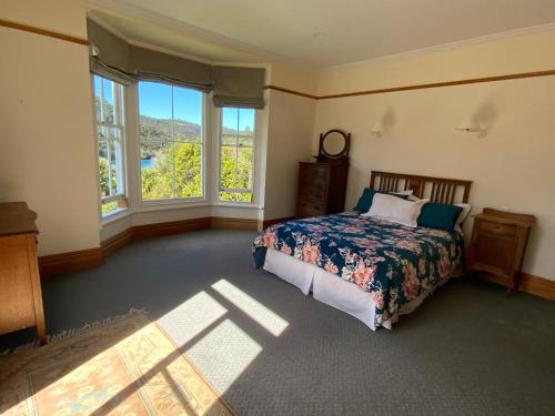 um quarto com uma cama e duas janelas em Glenfern Sanctuary em Port Fitzroy