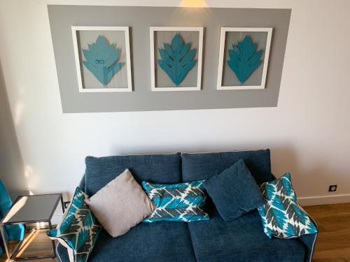 a blue couch in a living room with three pictures on the wall at Le Pétrel Noir - Appartement sur la plage des Roches Noires à Saint-Gilles-les-Bains in Saint-Gilles les Bains