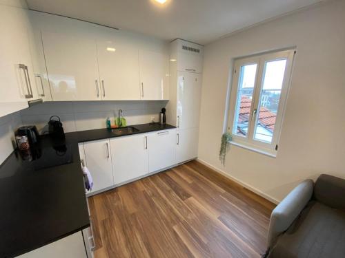 a small kitchen with white cabinets and a window at Apartment Seeblick in Arbon von Swisspartments in Arbon