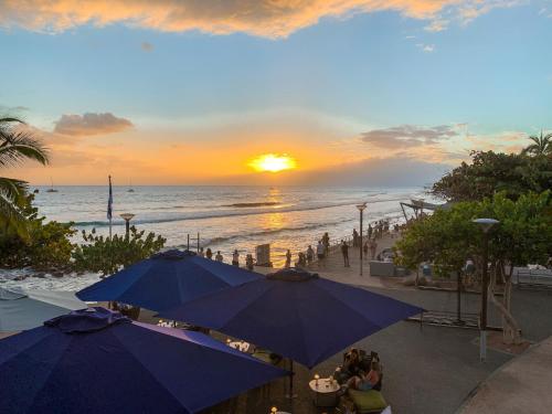 a view of a beach with umbrellas and the sunset at Le Pétrel Noir - Appartement sur la plage des Roches Noires à Saint-Gilles-les-Bains in Saint-Gilles les Bains
