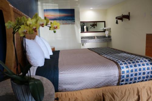 a bedroom with a bed and a vase with flowers at Valli Hi Motel in San Ysidro, San Diego