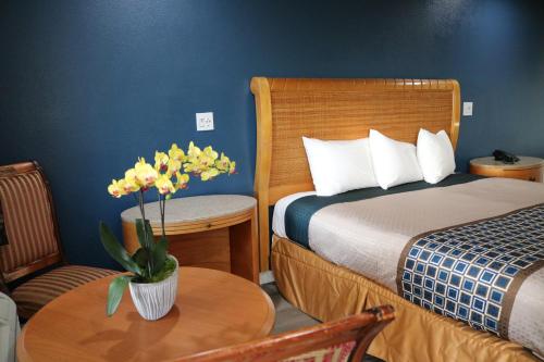 a hotel room with a bed and a table with flowers at Valli Hi Motel in San Ysidro, San Diego