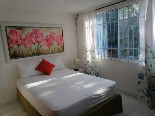 1 dormitorio con cama con almohada roja y ventana en Casa La Fe en Cartagena de Indias