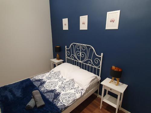 1 dormitorio con una pared azul, 1 cama y 2 mesas en Apartament Skandia Blue en Toruń