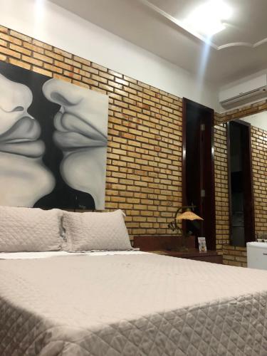 a bedroom with a bed and a brick wall at Hotel Mansão Marcieri in Aquiraz