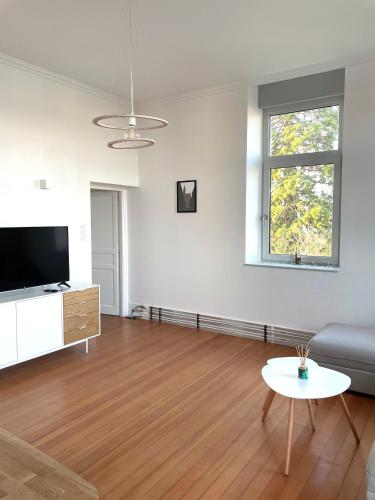 a living room with a couch and a tv and a table at Domaine Séquoia in Stutzheim