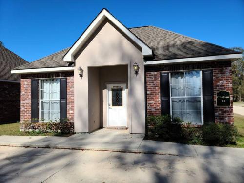 a brick house with a white door on a driveway at Chateau 18 in Hammond