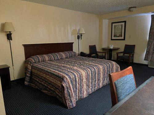 a hotel room with a bed and a table and chairs at Budget Inn Temple Hills in Temple Hills
