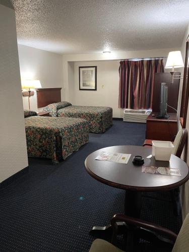 a hotel room with two beds and a table at Budget Inn Temple Hills in Temple Hills