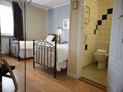 a bedroom with two beds and a bathroom with a toilet at Hotell Zlafen Bed and Breakfast in Karlskoga