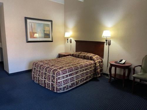 a hotel room with a bed and a chair at Budget Inn Temple Hills in Temple Hills