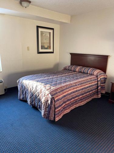 a hotel room with a bed with a blanket on it at Budget Inn Temple Hills in Temple Hills