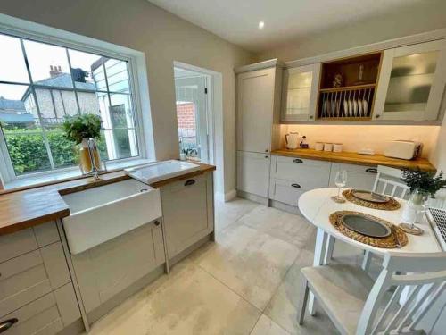 a kitchen with white cabinets and a sink and a table at Modern Cottage Style House with Log Burner in Harrogate