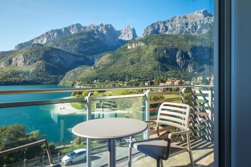 a balcony with a table and chairs and mountains at Hotel Fontanella in Molveno