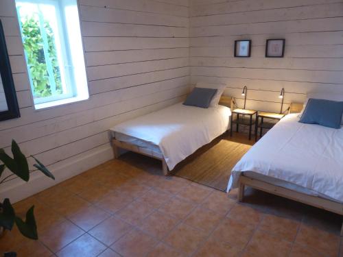 Habitación con 2 camas, mesa y 2 ventanas. en La Grange du Turc - Piscine partagée, en Le Mas-dʼAgenais