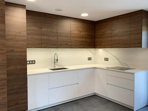 a kitchen with white cabinets and wooden walls at Cal Canal in Montferrer