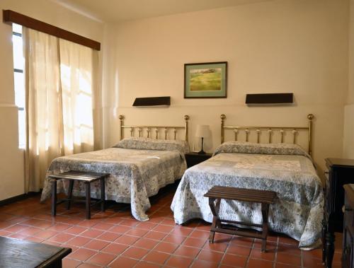 zwei Betten in einem Zimmer mit rotem Fliesenboden in der Unterkunft Hotel Rancho El Morillo in Saltillo