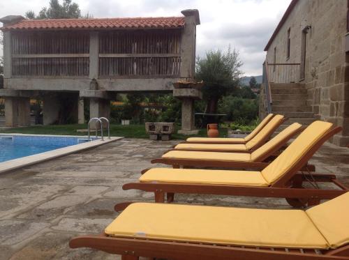 a row of lounge chairs next to a swimming pool at Casa da Ponte do Porto in Amares