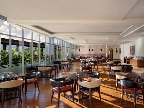 a restaurant with tables and chairs and windows at Radisson Golf & Convention Center Batam in Batam Center