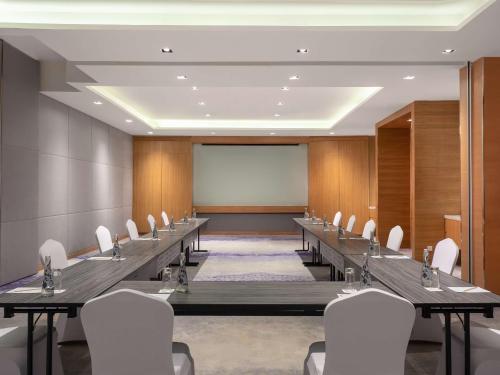 a conference room with long tables and white chairs at Radisson Golf & Convention Center Batam in Batam Center
