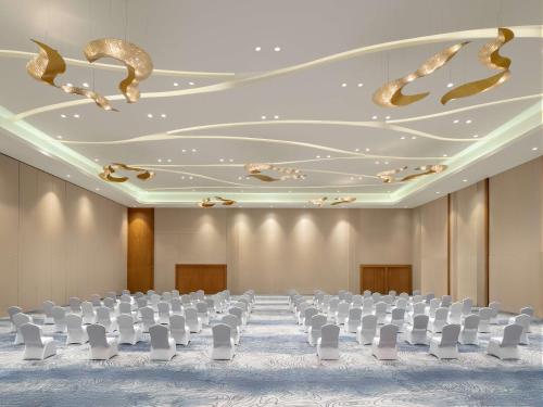 an empty banquet hall with white chairs and ceilings at Radisson Golf & Convention Center Batam in Batam Center