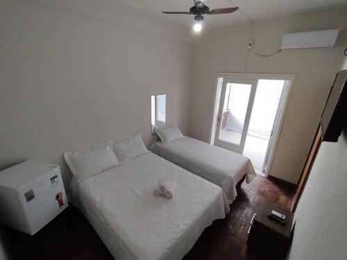 a small bedroom with two beds and a window at Hotel Kruger in Tramandaí