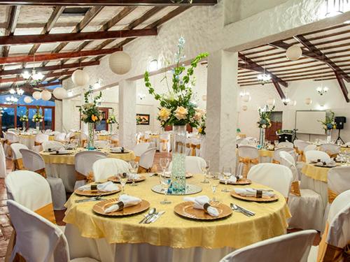 a banquet hall with white tables and white chairs at San Agustin Internacional Hotel in San Agustín