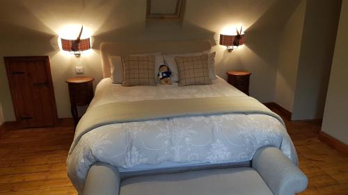 uma grande cama branca com um urso de peluche sentado nela em Gateshaw Cottage - Scottish Borders em Linton