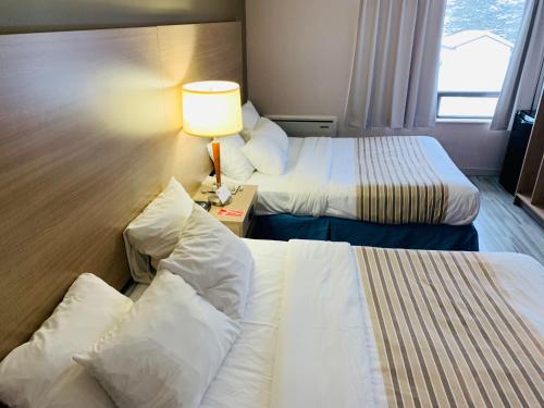 a hotel room with two beds and a lamp at Econo Lodge Airport Quebec in Quebec City