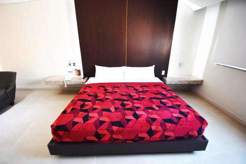 a bed with a red comforter in a room at Hotel Via La Villa in Mexico City