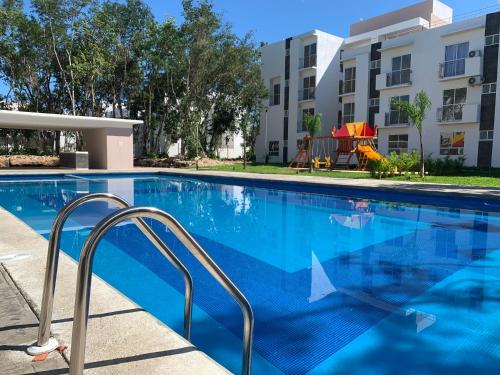 a swimming pool at a apartment complex with a building at Departamento Vacacional 2 habitaciones vista a la alberca by EITA in Cancún