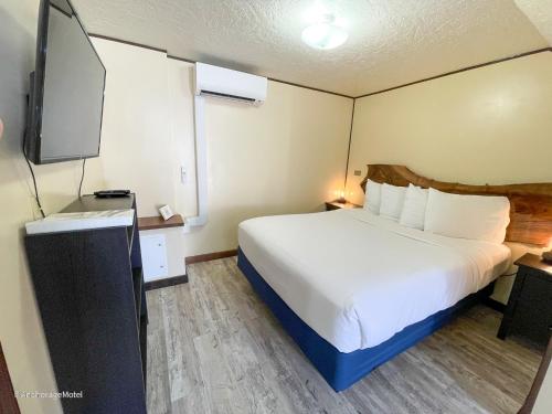 a hotel room with a bed and a flat screen tv at The Anchorage Motel in Pacific City