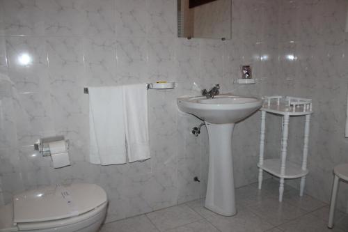 Baño blanco con lavabo y aseo en Restaurante Abba, en Póvoa de Lanhoso