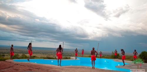 a group of people standing around a swimming pool at Oldarpoi Mara Camp in Keekorok