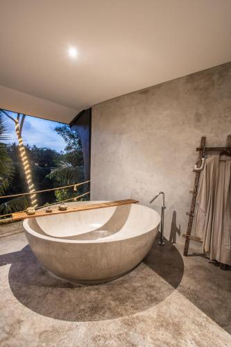 a bath tub in a bathroom with a large window at The Hidden Paradise Ubud - CHSE Certified in Ubud