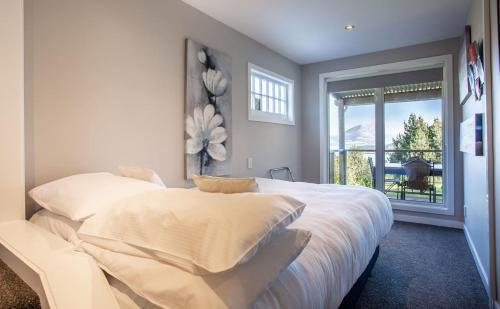 a bedroom with a large white bed with a window at Private Cottage with Spa and Amazing Lake Views in Closeburn