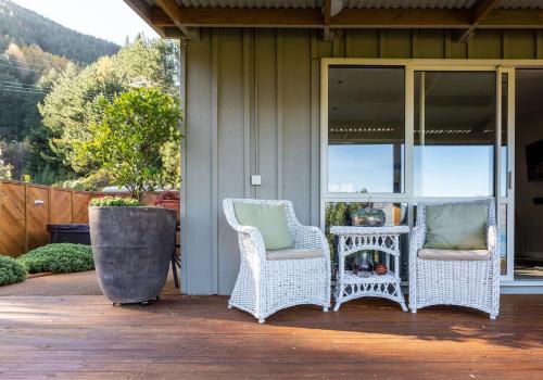 two wicker chairs and a table on a porch at Private Cottage with Spa and Amazing Lake Views in Closeburn