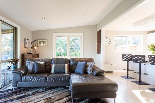 a living room with a brown leather couch at Private Cottage with Spa and Amazing Lake Views in Closeburn