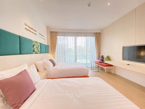 a hotel room with two beds and a flat screen tv at The Poem Hotel in Mae Pim