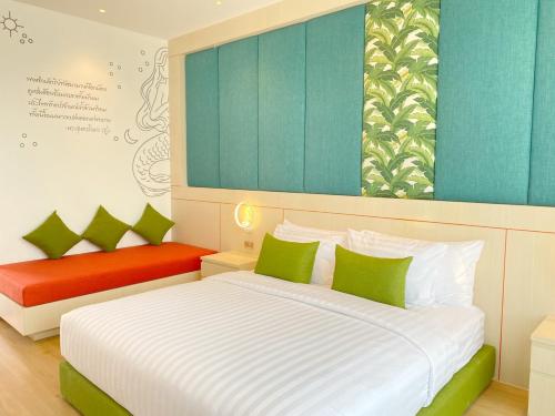 a bedroom with a bed with green and red pillows at The Poem Hotel in Mae Pim
