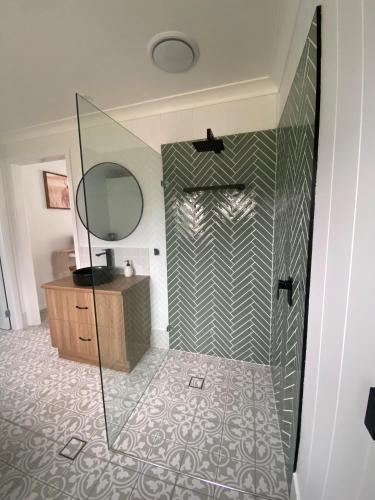 a bathroom with a shower with a mirror and a sink at Studio 69 on Capper in Tumut