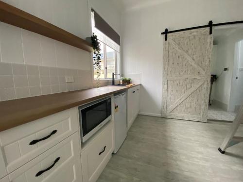 a kitchen with white cabinets and a sliding barn door at Studio 69 on Capper in Tumut