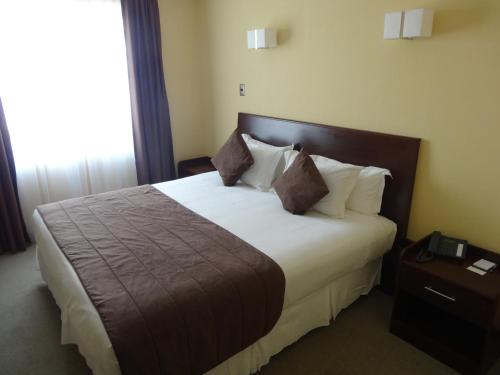 a bedroom with a large bed with white sheets and pillows at Hotel Costa Pacifico - Express in Antofagasta