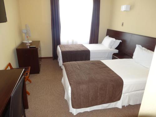 a hotel room with two beds and a television at Hotel Costa Pacifico - Express in Antofagasta