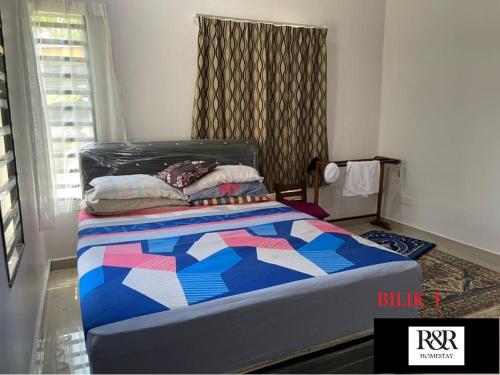 a bedroom with a bed with a colorful quilt on it at R & R HOMESTAY in Tanjung Karang