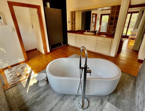 a white bath tub in a bathroom with a sink at Imani Bush House & Silver Sky Chalet in Hluhluwe