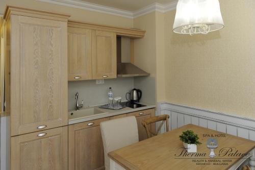 a kitchen with wooden cabinets and a wooden table at Therma Palace - All inclusive & Private Beach & Free Parking in Kranevo