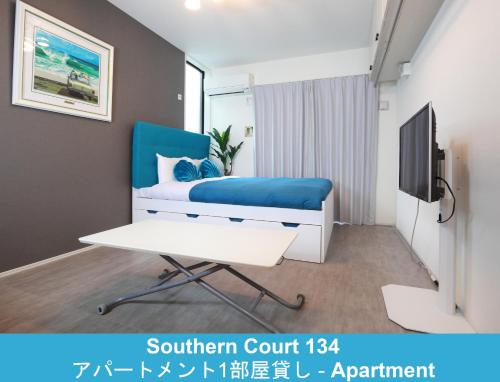 a bedroom with a blue bed and a tv at Enoshima Guest House 134 in Fujisawa