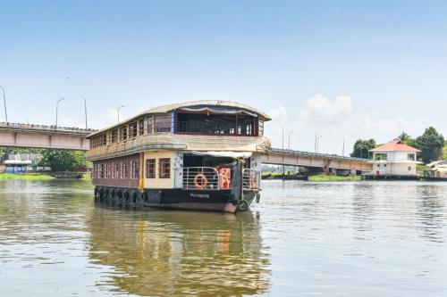 a ferry boat on the water with a bridge in the background at Beach Paradise Day Cruise Houseboat in Alleppey