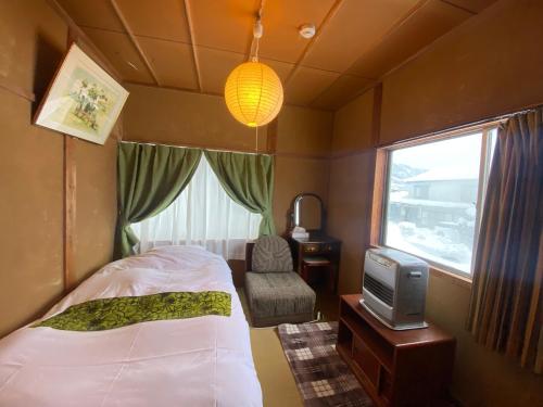 a bedroom with a bed and a tv and a window at HAKUBA Raicho Star in Hakuba